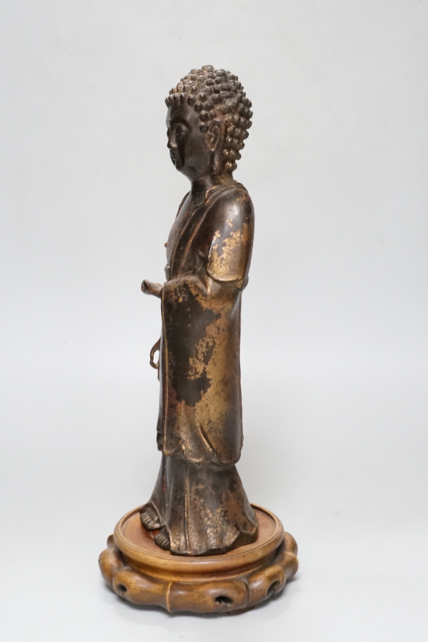 A Chinese gilt lacquered bronze standing figure of Buddha on stand, 31cm high not including stand